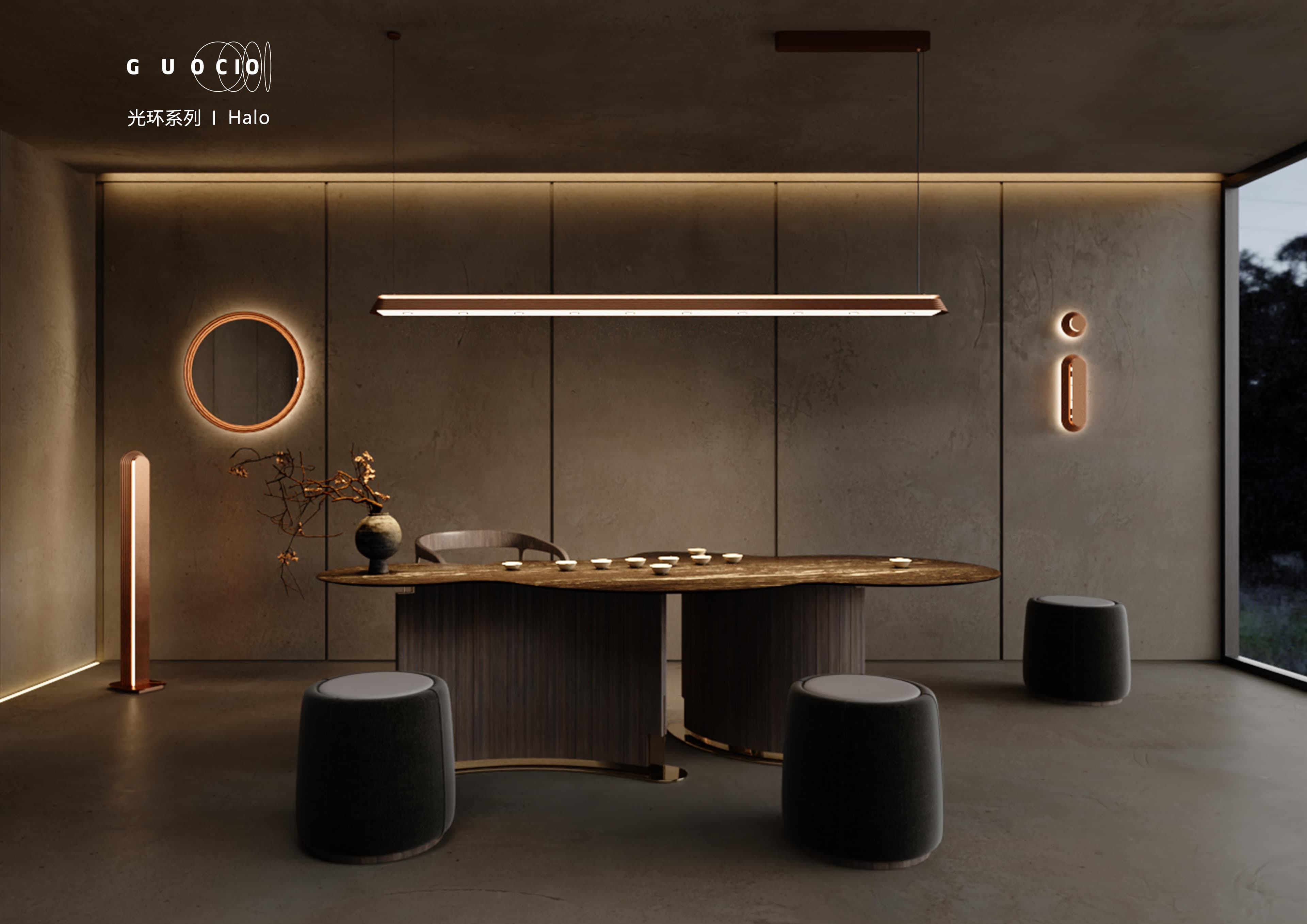 A modern room with concrete walls features a long, linear pendant light over a wooden table, accompanied by a circular mirror with backlighting, a tall floor lamp, and two wall-mounted lights shaped like an 'i', with dark upholstered stools around the table.