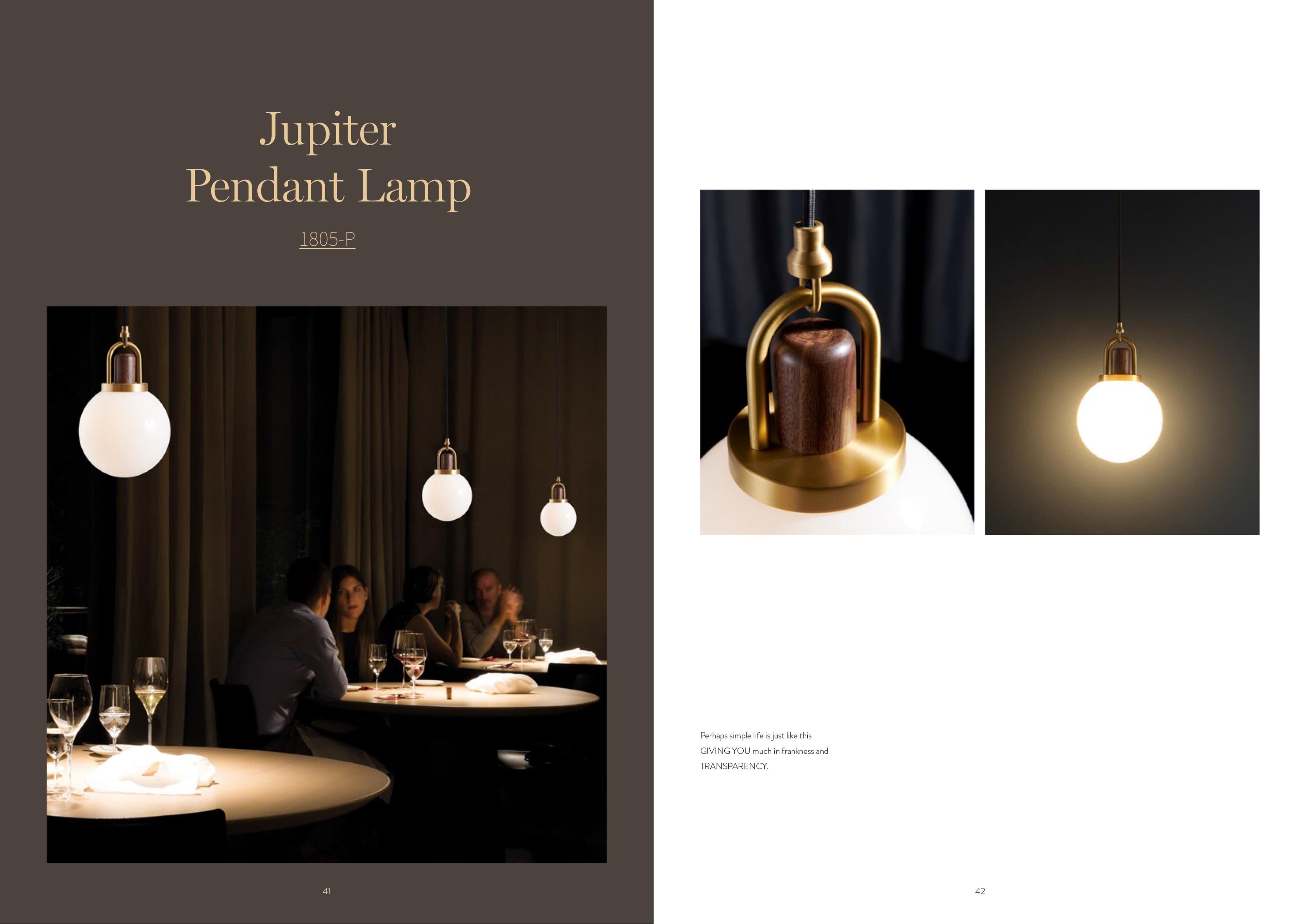 A Jupiter pendant lamp with a white spherical shade, brass accents, and a wooden top, is shown in a close-up and in a restaurant setting with people dining.